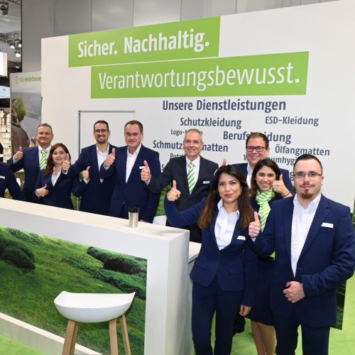 diemietwaesche.de Personal auf der Messe A+A 2019, alle in Anzug und den Daumen hoch haltend