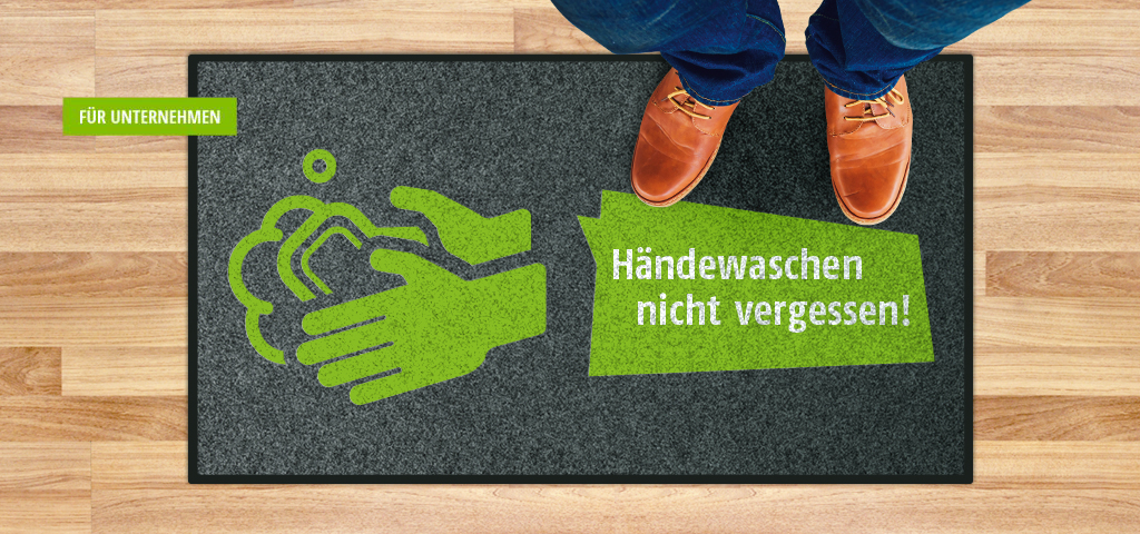 Mann mit blauer Jeans und braunen Lederschuhen steht auf Matte; Text: Händewaschen nicht vergessen!