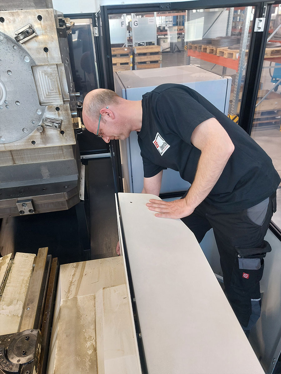 Geerds-Mitarbeiter in grauer Arbeitskleidung (T-Shirt, Hose) arbeitet an Maschine