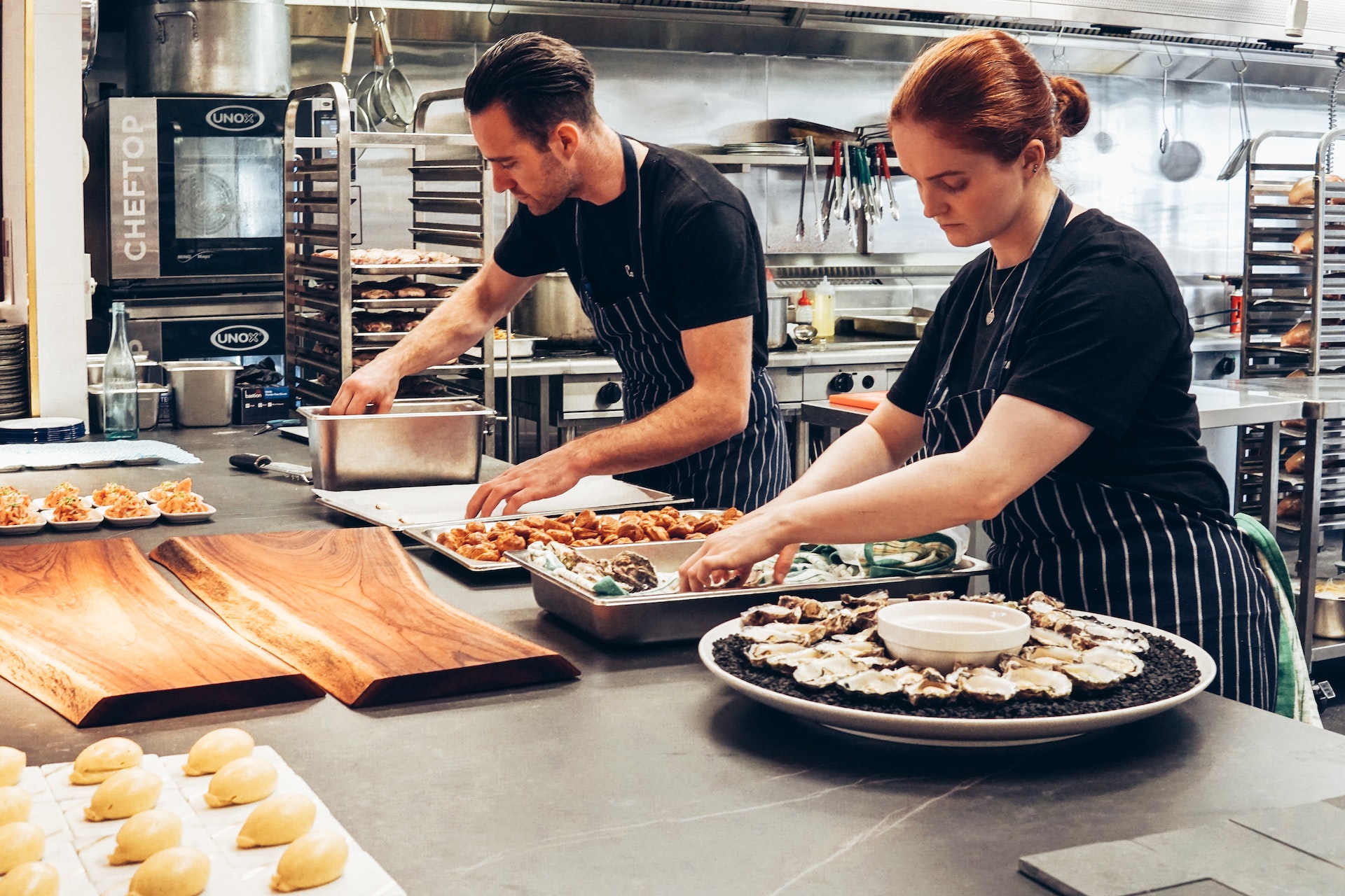 Zwei Köche in Restaurantküche, die Kochschürze tragen und Essen zubereiten