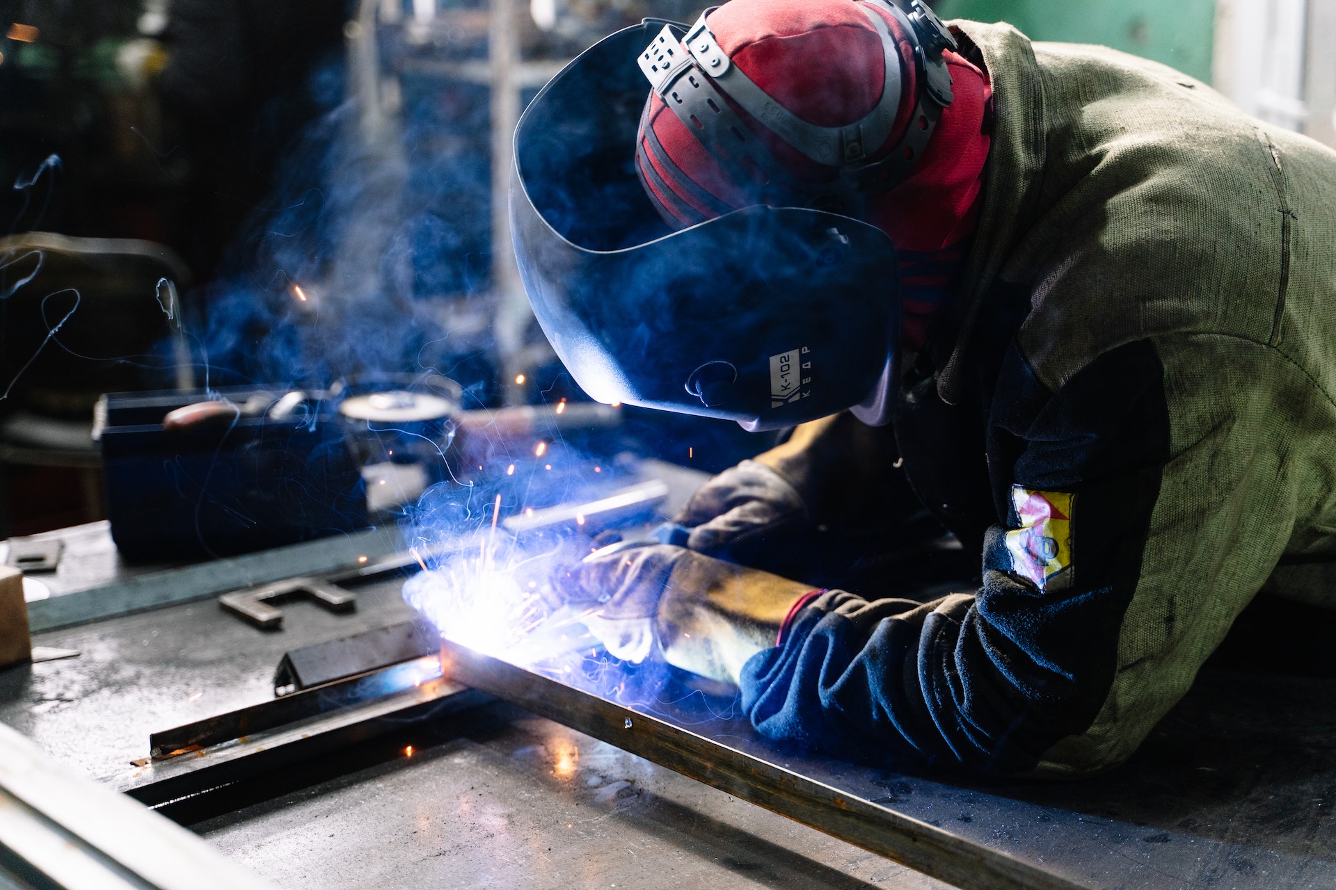 Schweißer in Schweißerschutzkleidung und Schweißmaske, der auf der Arbeit schweißt