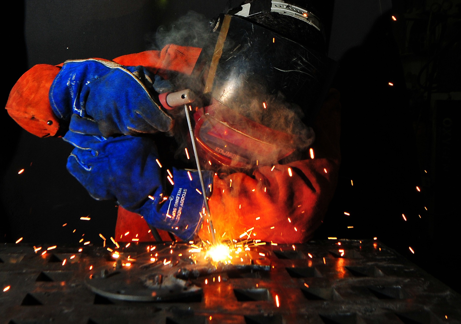 Schweißer in Schweißerschutzkleidung und Schweißmaske, der auf der Arbeit schweißt
