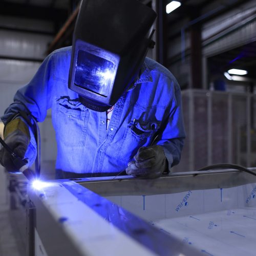 Schweißer in Schweißerschutzkleidung und Schweißmaske, der auf der Arbeit schweißt