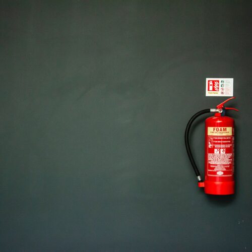 Schaumfeuerlöscher, der an grauer Wand hängt