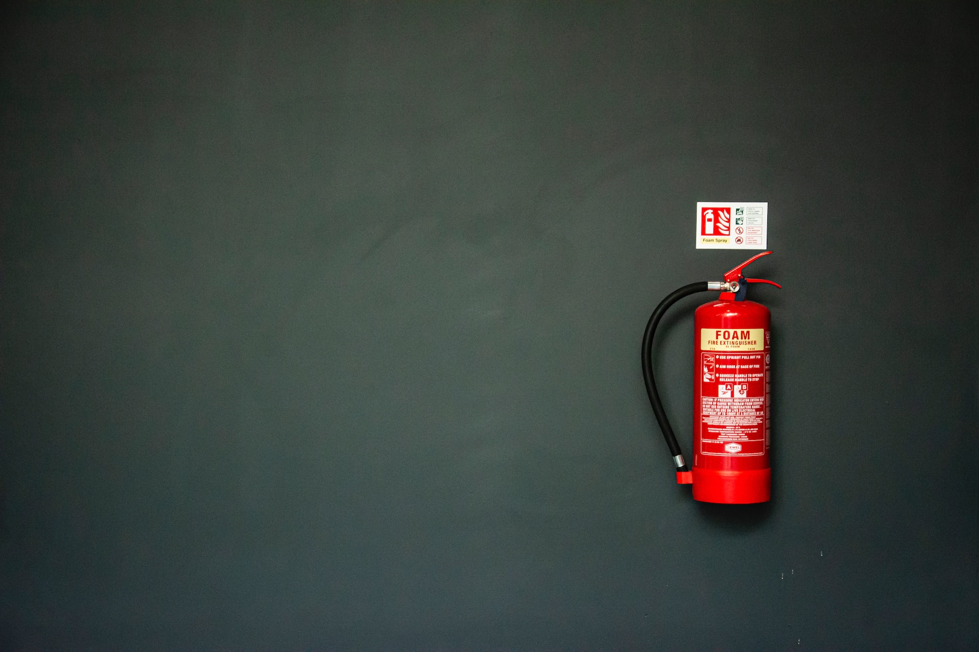 Schaumfeuerlöscher, der an grauer Wand hängt
