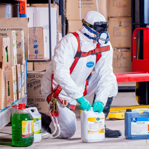 Arbeiter in kompletter Chemikalienschutzausrüstung in Lagerhallle