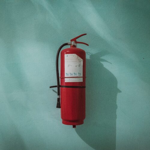 Feuerlöscher an türkisfarbener Wand