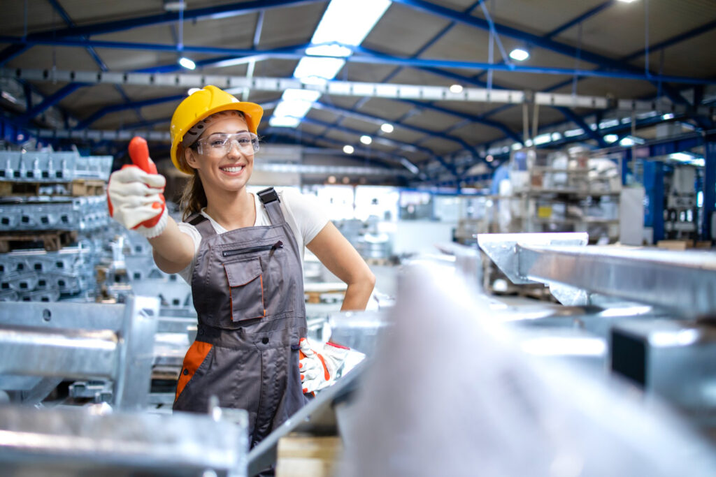 Arbeiterin in PSA, die in die Kamera lächelt und den Daumen hochhält