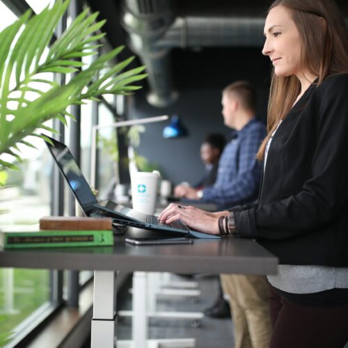 Frau, die am Arbeitsplatz steht und am Laptop arbeitet