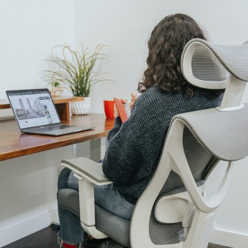Frau, die an Arbeitsplatz auf ergonomischem Bürostuhl sitzt