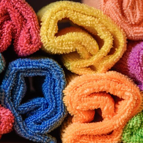 Bunte, zusammengerollte Mikrofasertücher in verschiedenen Farben, darunter Rot, Gelb, Blau, Orange, Lila und Grün, präsentiert in einer Nahaufnahme