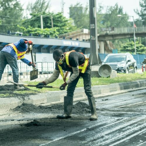 Arbeiter reparieren Straße neben Bushaltestelle im urbanen Gebiet bei Tageslicht.