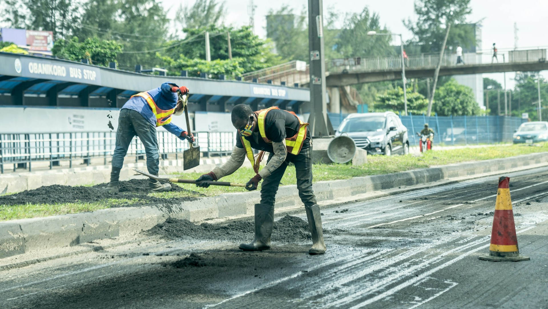 Arbeiter reparieren Straße neben Bushaltestelle im urbanen Gebiet bei Tageslicht.